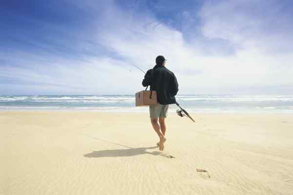 man walking on beach with fish rod