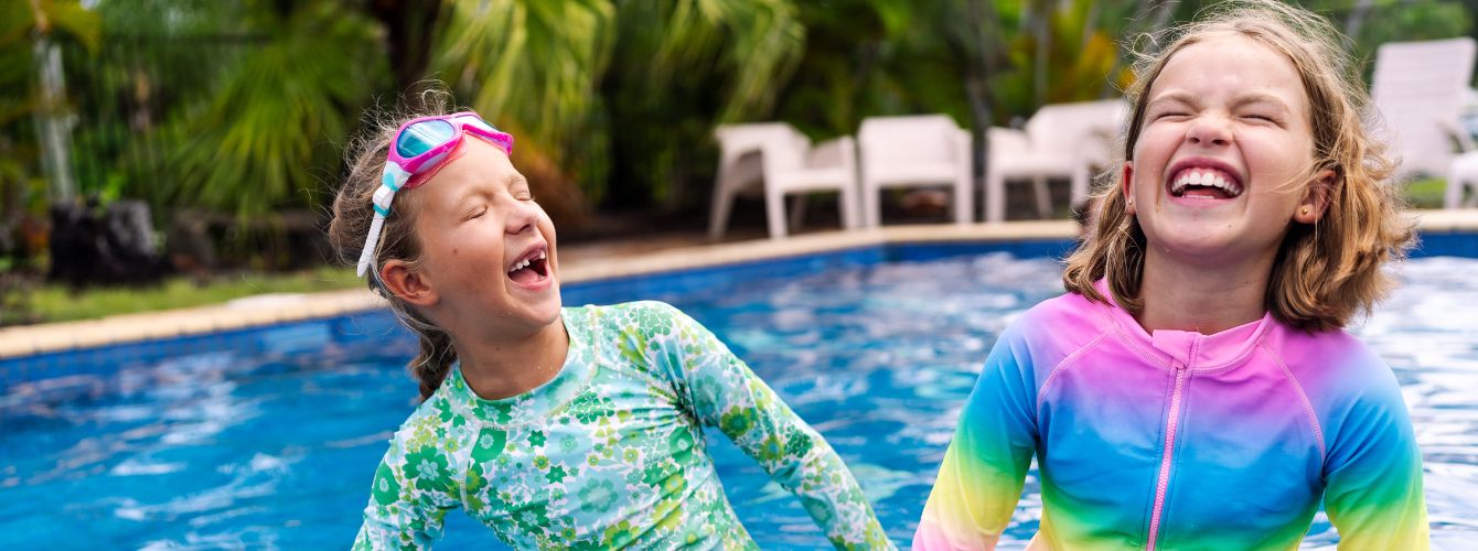 Two children sitting on the edge of a pool